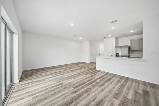 a view of kitchen with kitchen island a sink wooden floor and a refrigerator