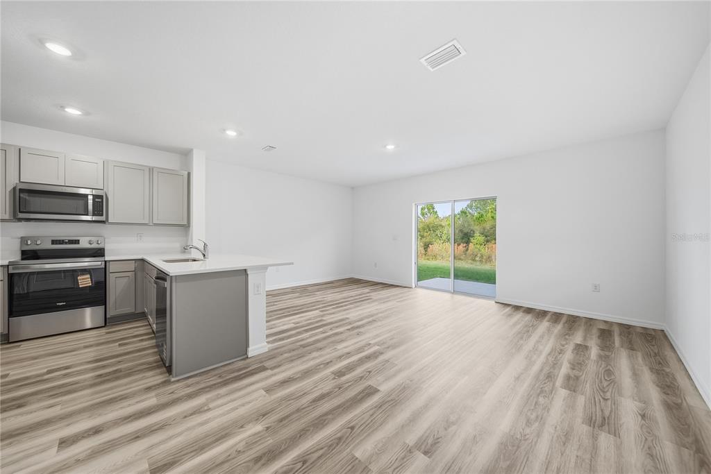 32497 Midsummer Night Lane Wesley Chapel, FL 33543 - Photo 5 of 30 a kitchen with wooden floors and stainless steel appliances