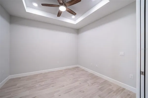 an empty room with chandelier fan and windows