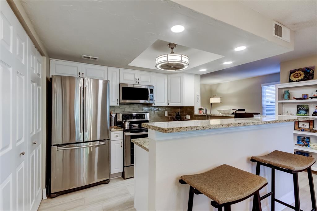 1407 Lennox Road East, Unit 1407 Palm Harbor, FL 34683 - Photo 12 of 48 a kitchen with stainless steel appliances a refrigerator stove microwave and cabinets