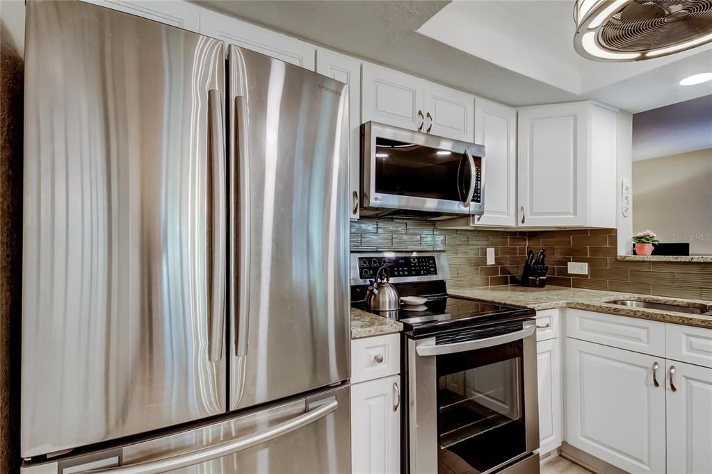 1407 Lennox Road East, Unit 1407 Palm Harbor, FL 34683 - Photo 14 of 48 a kitchen with stainless steel appliances a refrigerator stove and microwave