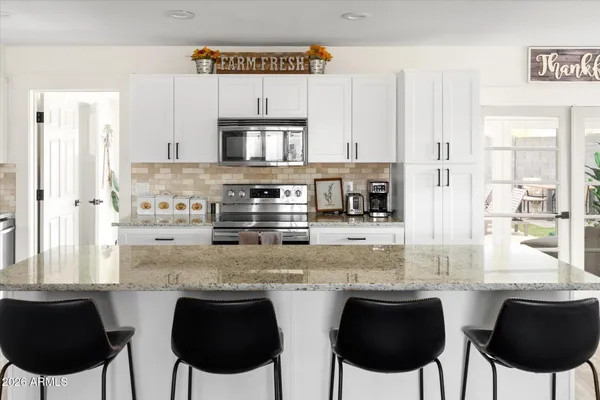 a kitchen with granite countertop a sink and white cabinets