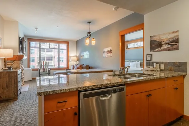 a kitchen with stainless steel appliances granite countertop a sink a stove and a wooden cabinets