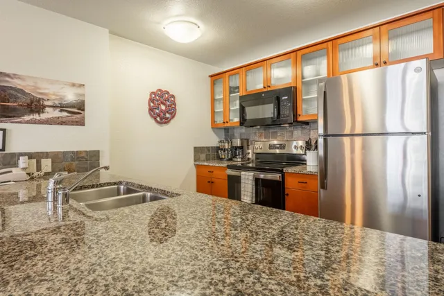a kitchen with granite countertop a refrigerator and a stove top oven