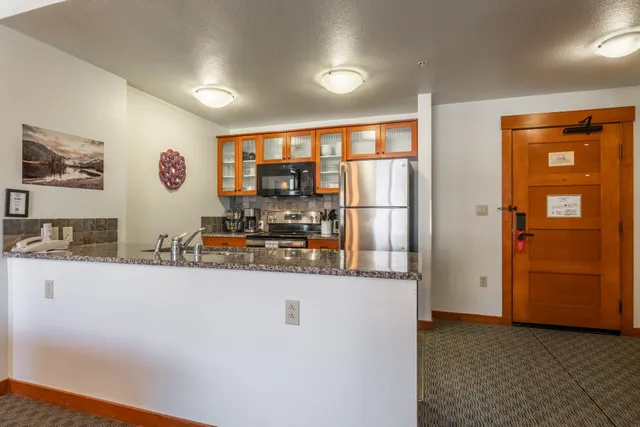 a view of a kitchen with fridge and wooden floor