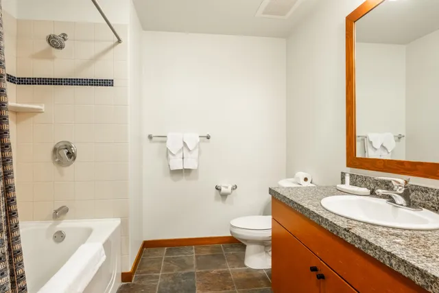 a bathroom with a granite countertop sink a toilet and shower
