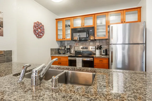a kitchen with stainless steel appliances granite countertop a refrigerator and a stove top oven