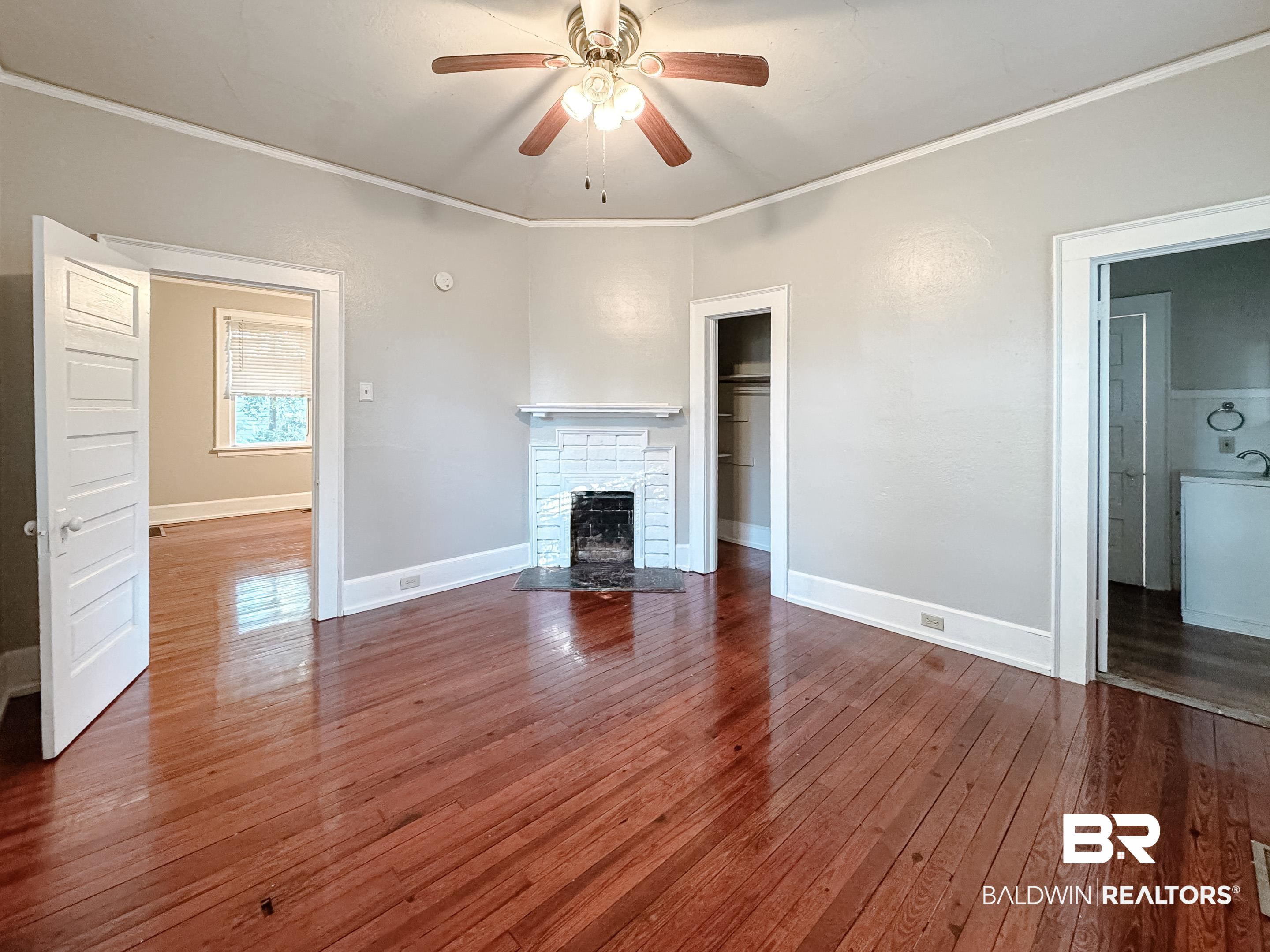206 1st Street Mobile, AL 36611 - Photo 18 of 26 Unfurnished living room featuring a fireplace with flush hearth, dark wood-style floors, ornamental molding, and a ceiling fan