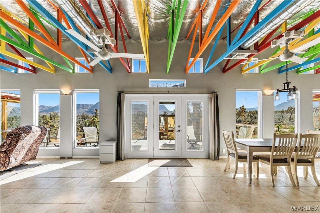 26512 North Yucca Road Meadview, AZ 86444 - Photo 18 of 38 Spacious living area featuring tiled flooring, a high ceiling with exposed colorful beams and ceiling fans, and large windows offering expansive views of the surrounding landscape
