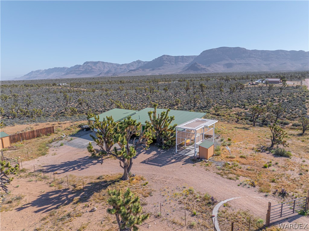26512 North Yucca Road Meadview, AZ 86444 - Photo 2 of 38 The property features a home with a green roof, a covered outdoor structure, and a fenced area