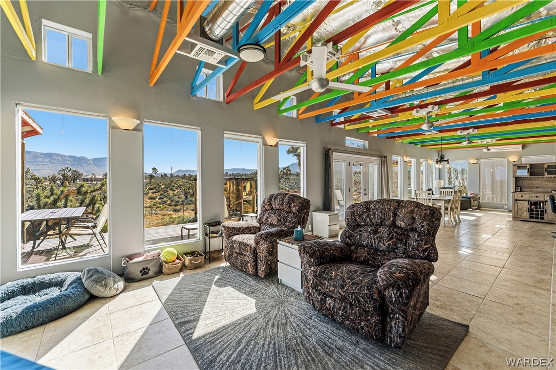 26512 North Yucca Road Meadview, AZ 86444 - Photo 25 of 38 This spacious living area features high ceilings with exposed, brightly colored ceiling beams, tile flooring, and large windows that provide abundant natural light and expansive views of the surrounding landscape