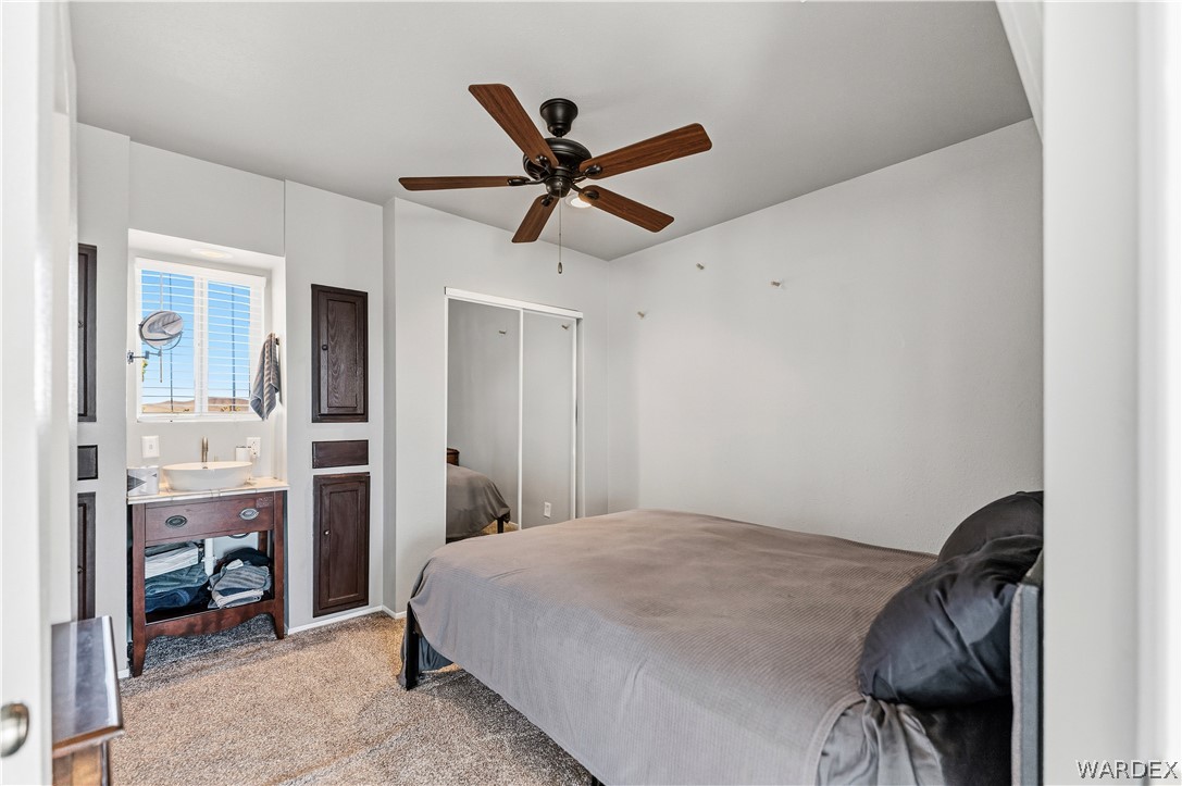 26512 North Yucca Road Meadview, AZ 86444 - Photo 31 of 38 This room features neutral-toned carpet flooring, a ceiling fan with wooden blades, and a window with horizontal blinds