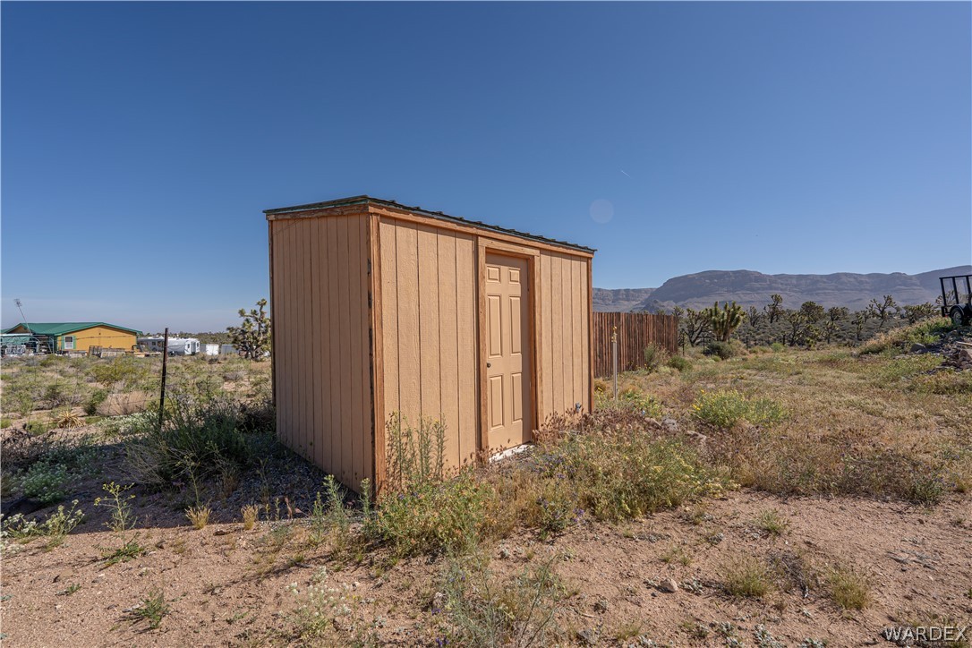 26512 North Yucca Road Meadview, AZ 86444 - Photo 37 of 38 The property includes a detached shed with a panel siding exterior and a single door, situated on a land lot with natural vegetation