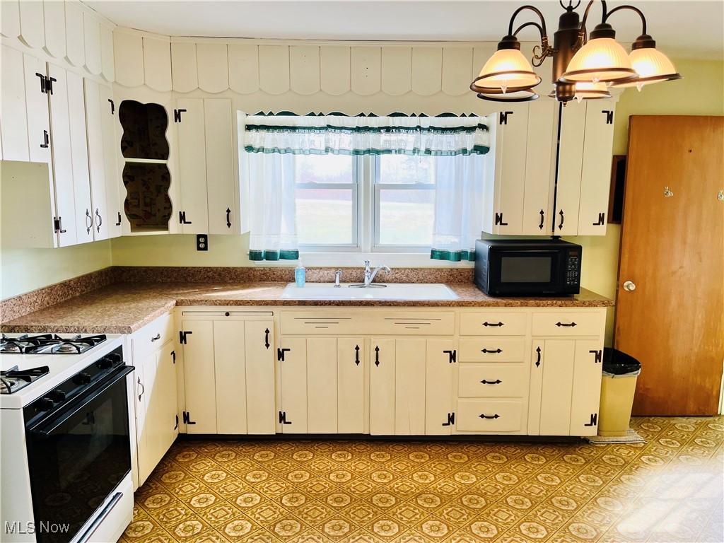 3210 Austinburg Road Ashtabula, OH 44004 - Photo 25 of 48 Kitchen with decorative light fixtures, gas range oven, white cabinetry, a sink, and black microwave