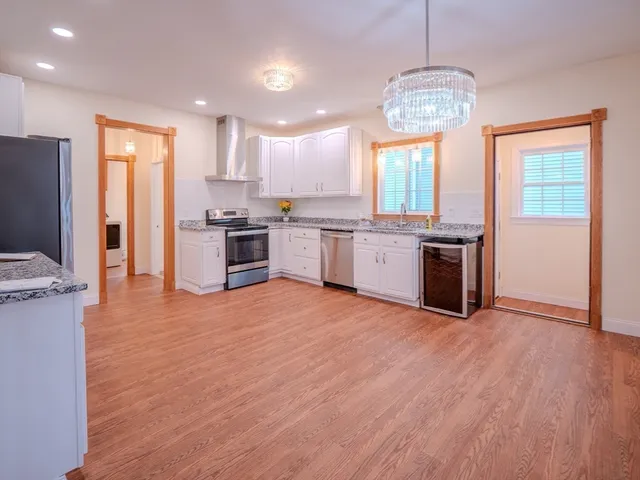 a open kitchen with stainless steel appliances granite countertop a stove top oven a sink dishwasher a refrigerator and cabinets with wooden floor