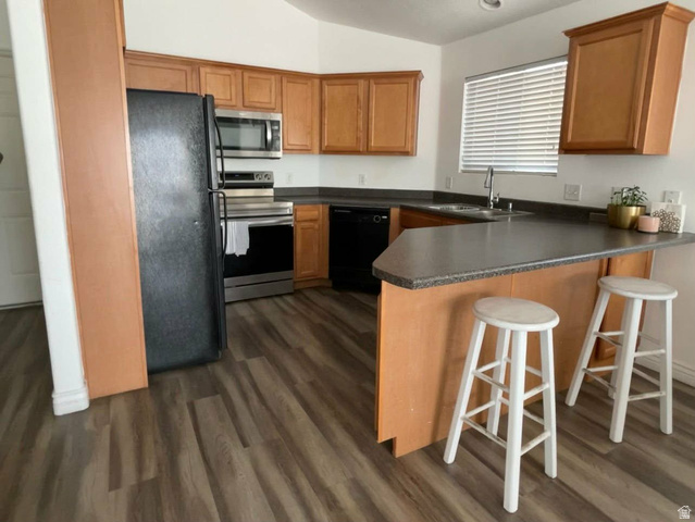 90 East Resaca Drive, Unit C11 Sandy, UT 84070 - Photo 6 of 27 Kitchen with a peninsula, black appliances, dark countertops, lofted ceiling, and a breakfast bar