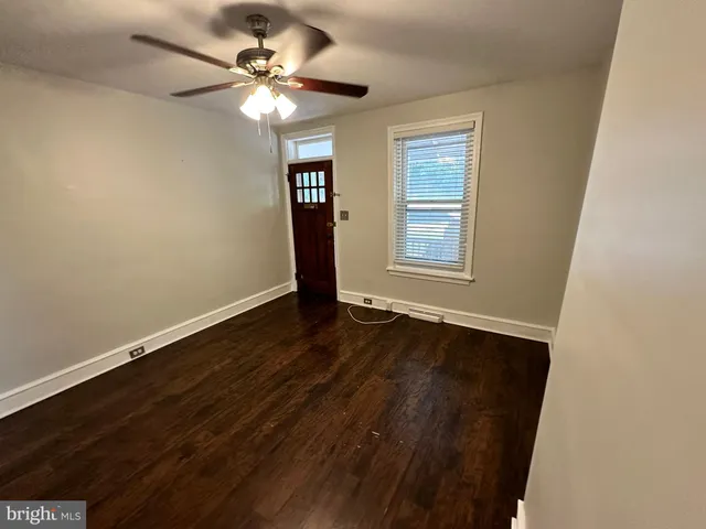 an empty room with wooden floor chandelier fan and windows