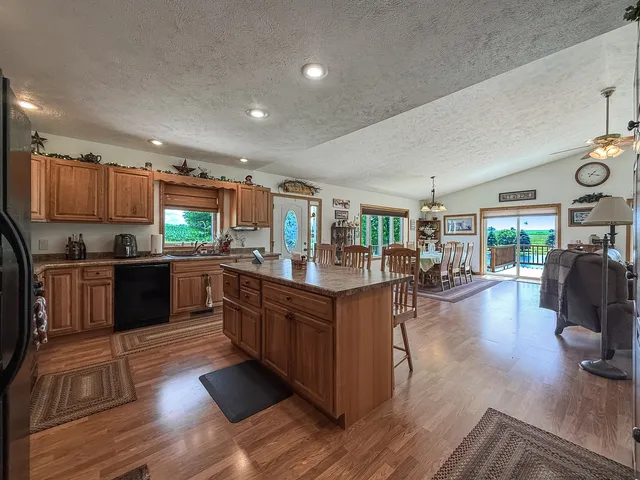 a kitchen with stainless steel appliances kitchen island granite countertop a refrigerator a stove a sink and a dining table with wooden floor