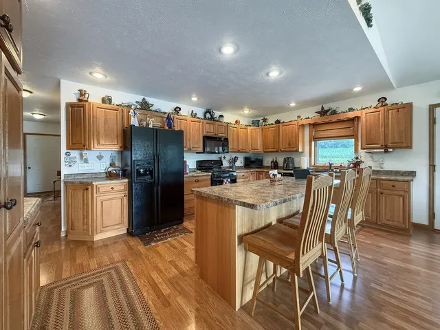 a kitchen with stainless steel appliances kitchen island granite countertop a table and chairs in it