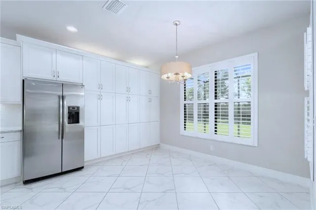 a large white kitchen with kitchen island a sink a counter top and stainless steel appliances