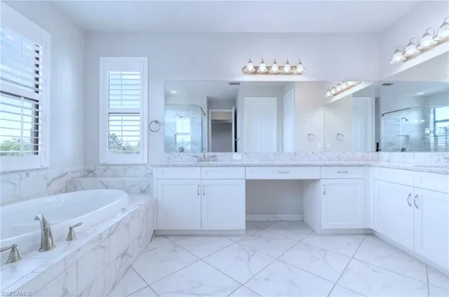 a spacious bathroom with a granite countertop sink a mirror and a bathtub