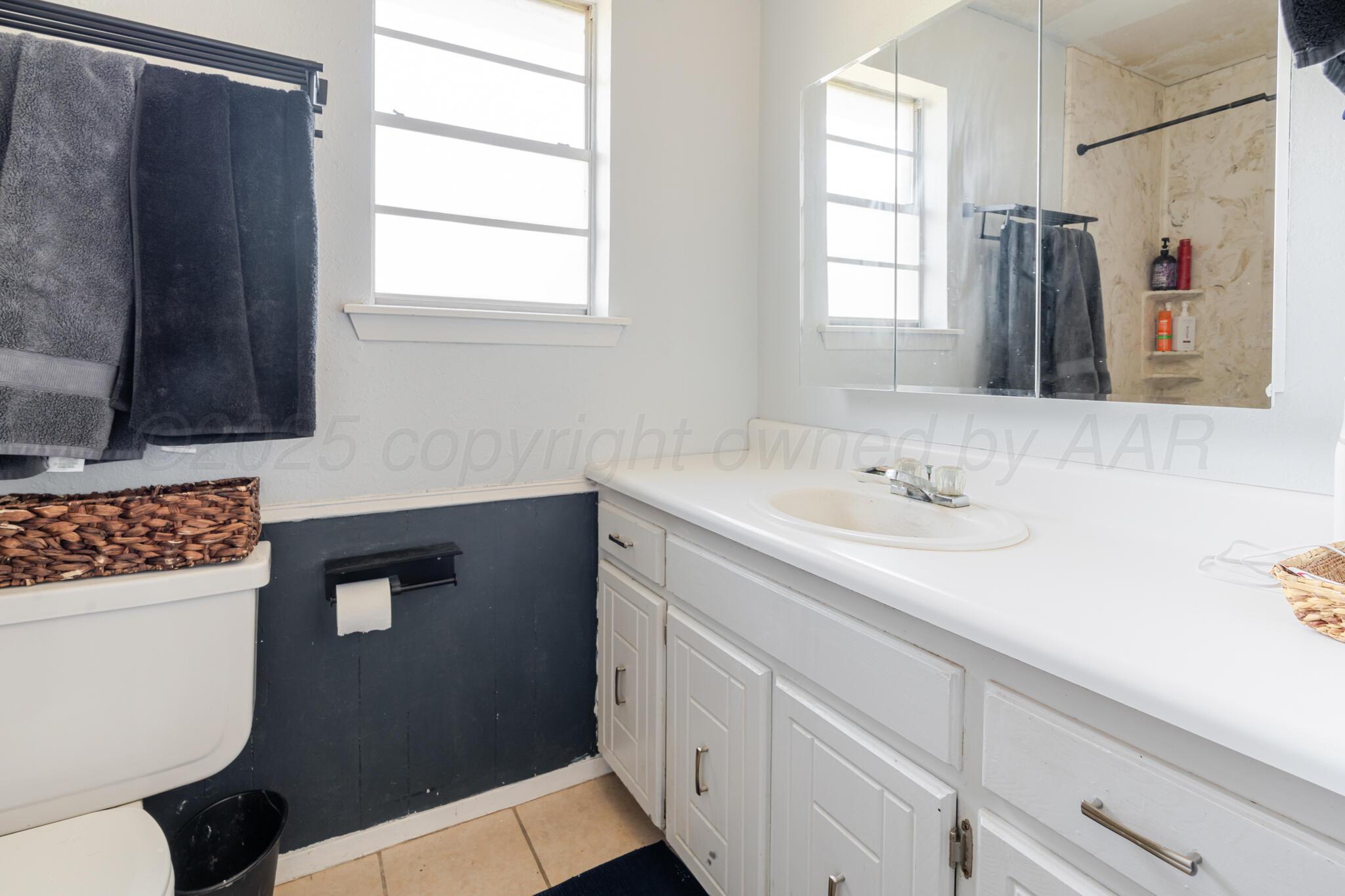 5210 South Milam Street Amarillo, TX 79110 - Photo 14 of 22 a bathroom with a sink a toilet a window and mirror