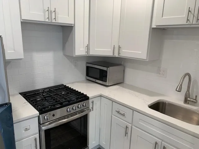 a kitchen with white cabinets and appliances