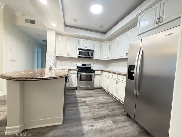 a kitchen with stainless steel appliances granite countertop a refrigerator sink and microwave