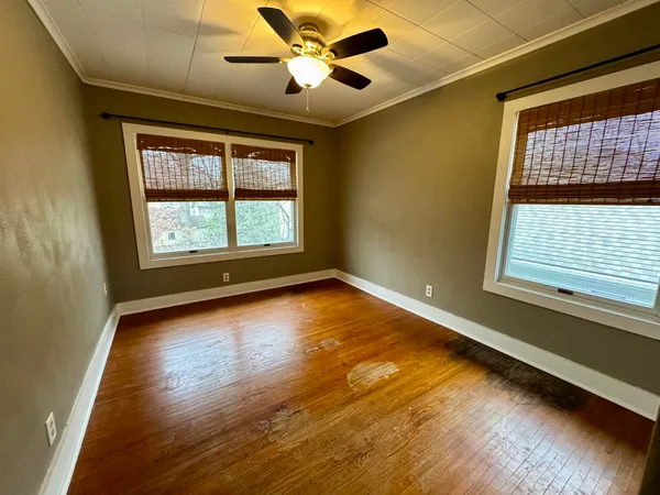 a view of an empty room with wooden floor and a window