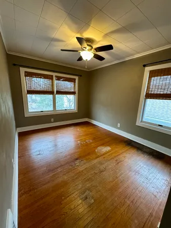 an empty room with wooden floor and fan