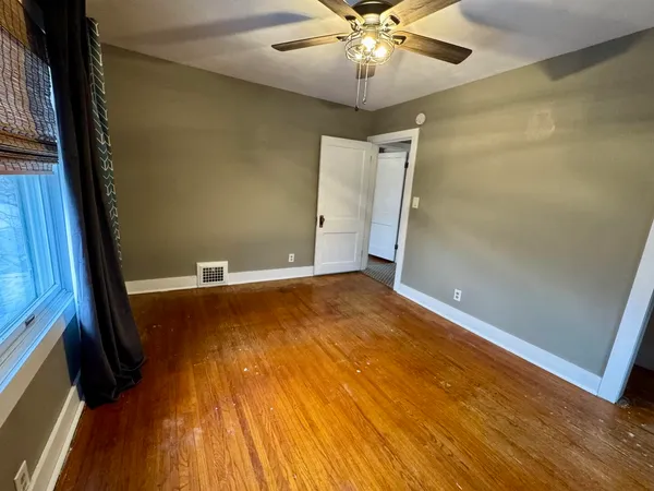 a view of an empty room with a window and wooden floor
