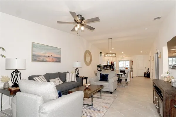 a living room with couches a dining table and kitchen view with wooden floor