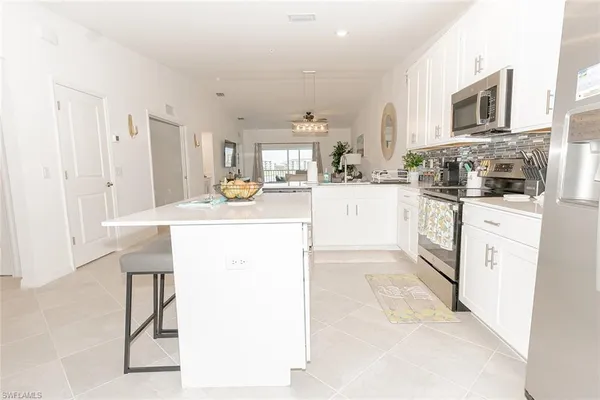 a kitchen with stainless steel appliances kitchen island granite countertop a stove top oven a sink a dining table and chairs