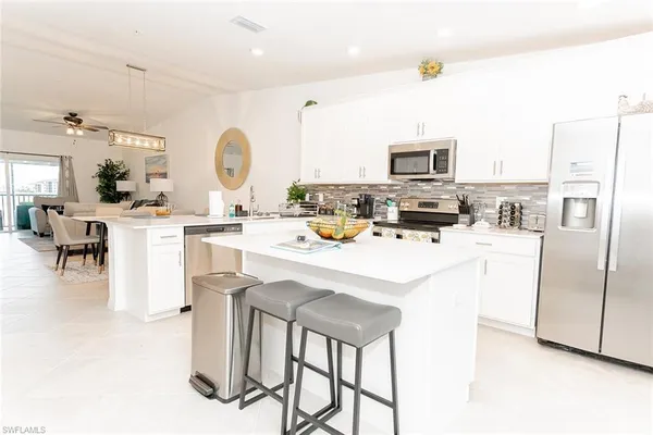 a kitchen with stainless steel appliances kitchen island granite countertop a stove a sink a dining table and chairs