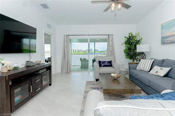 a living room with furniture floor to ceiling window and a flat screen tv