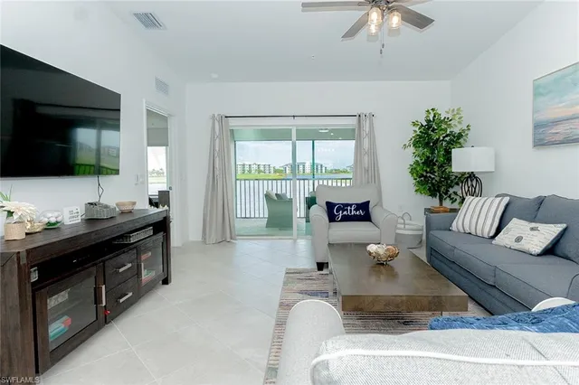 a living room with furniture floor to ceiling window and a flat screen tv