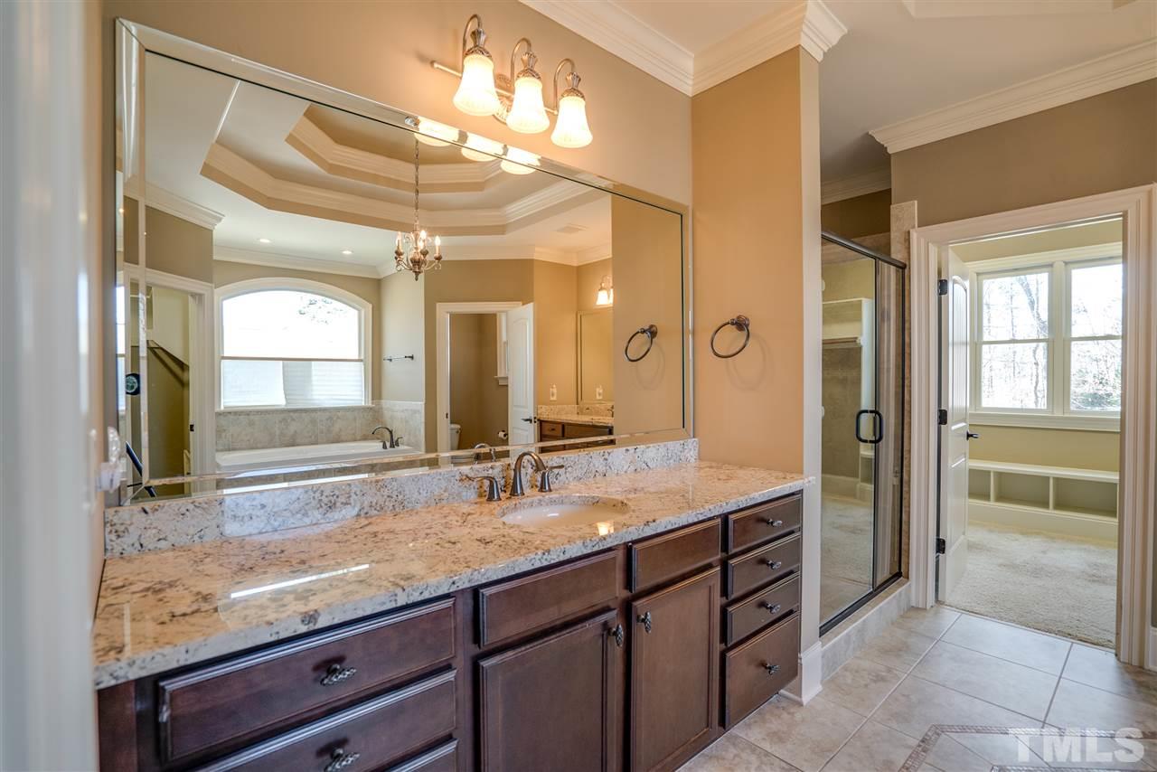 9008 Albatross Court Raleigh, NC 27613 - Photo 17 of 25 a bathroom with a granite countertop sink a large mirror and a shower
