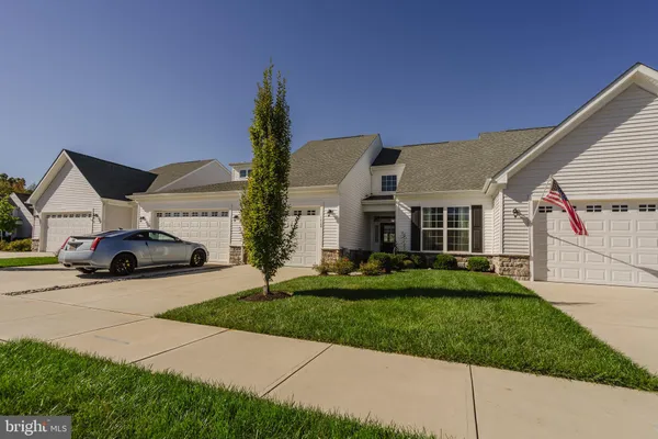 a view of a white house next to a yard with big trees
