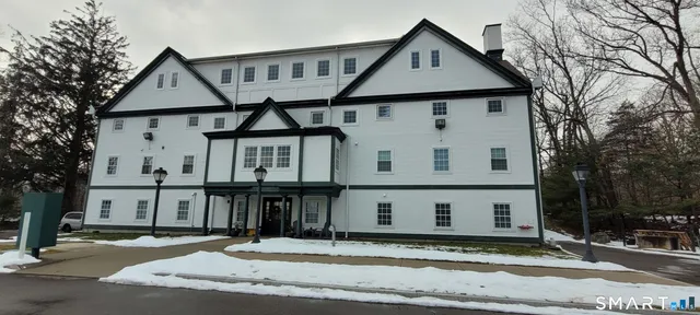 a view of a white house with a large tree