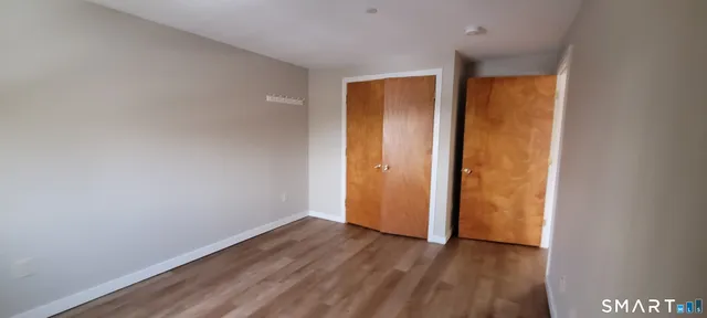 a view of an empty room with wooden floor and closet