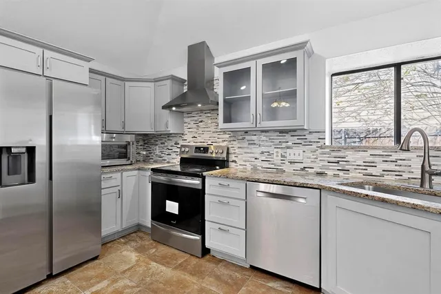 a kitchen with stainless steel appliances granite countertop a sink a stove and refrigerator