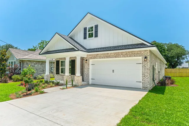 a front view of a house with a yard and potted plants