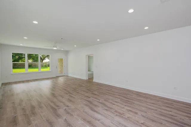 a view of an empty room with a window and wooden floor