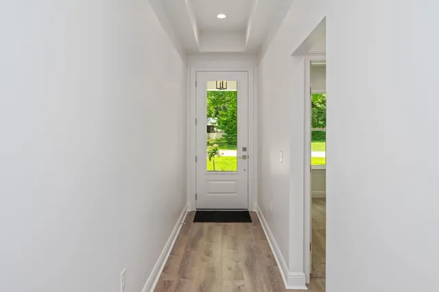 a view of an empty room with wooden floor and a kitchen
