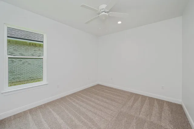 an empty room with a window and ceiling fan