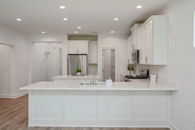 a kitchen with stainless steel appliances a refrigerator sink and white cabinets