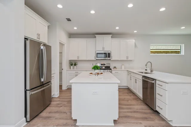 a kitchen with stainless steel appliances granite countertop white cabinets a stove a microwave and a refrigerator