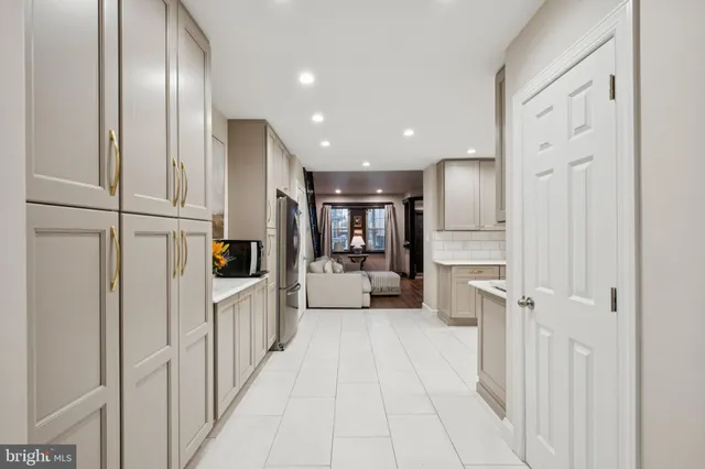 a view of a kitchen with refrigerator and white cabinets