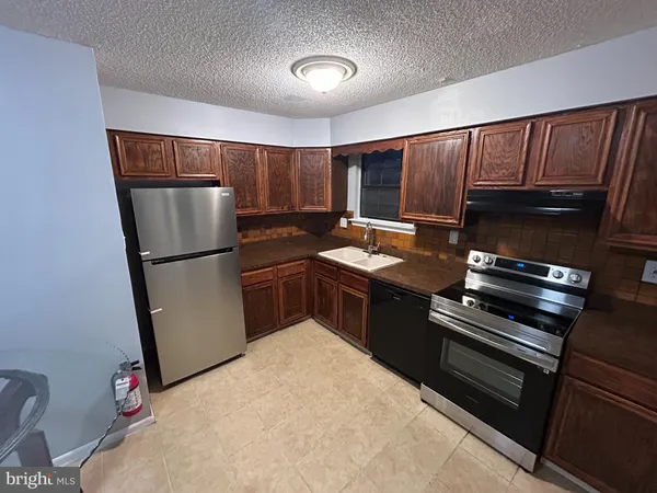 a kitchen with granite countertop a refrigerator and a stove top oven