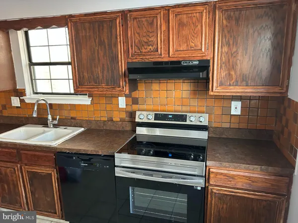 a kitchen with granite countertop a sink stove and cabinets